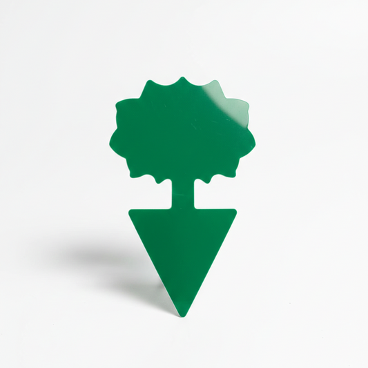 Gros plan sur un piège adhésif de couleur verte en forme de fleur stylisée. Le dispositif dispose d'un piquet à sa base pour être inséré dans la terre et sert à capturer les thrips et mouches de terreau.