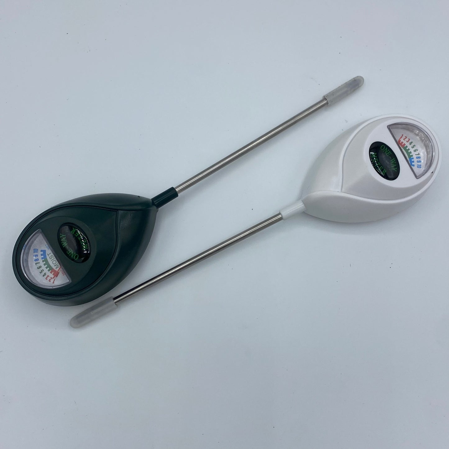 Gros plan sur deux testeurs d'humidité de sol (noir et blanc) avec leurs sondes métalliques, posés sur un fond clair. Outil essentiel pour le jardinage et l'entretien des plantes d'intérieur.