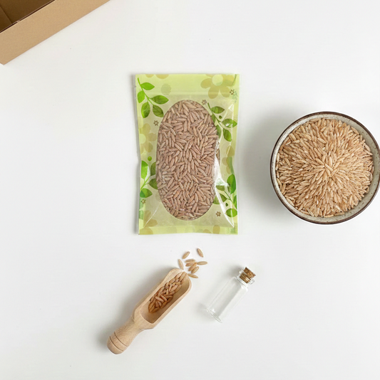 Vue aérienne sur fond blanc d'un sachet de graines, d'un bol rempli de semences, d'une petite pelle en bois et d'une boîte en carton ouverte, illustrant un kit de plantation.