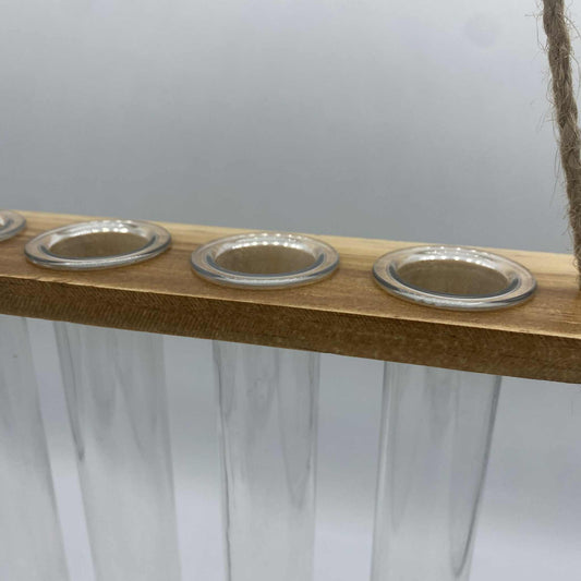 Un support de bouturage suspendu en bois clair avec quatre tubes à essai en verre, conçu pour la propagation de plantes d'intérieur.