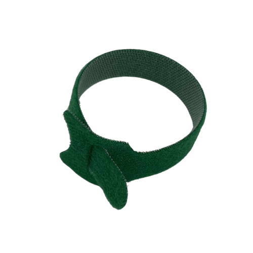 Une attache de jardin en velcro, de couleur vert foncé, est vue sous un angle légèrement surélevé. Elle a une texture veloutée sur un côté et est montrée partiellement attachée, formant un cercle lâche. Le fond est blanc, ce qui met en valeur la forme et la couleur de l'attache.