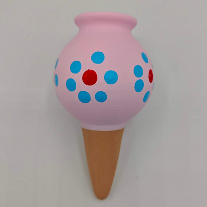 Un cône d'arrosage goutte à goutte pour plantes d'intérieur, en céramique peinte en rose avec des points rouges et bleus.