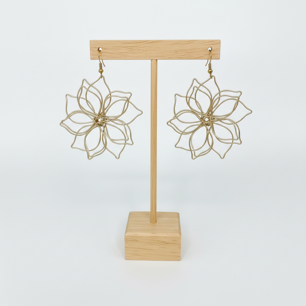Paire de boucles d'oreilles artisanales en forme de fleur présentées sur un support en bois clair, fond blanc épuré.