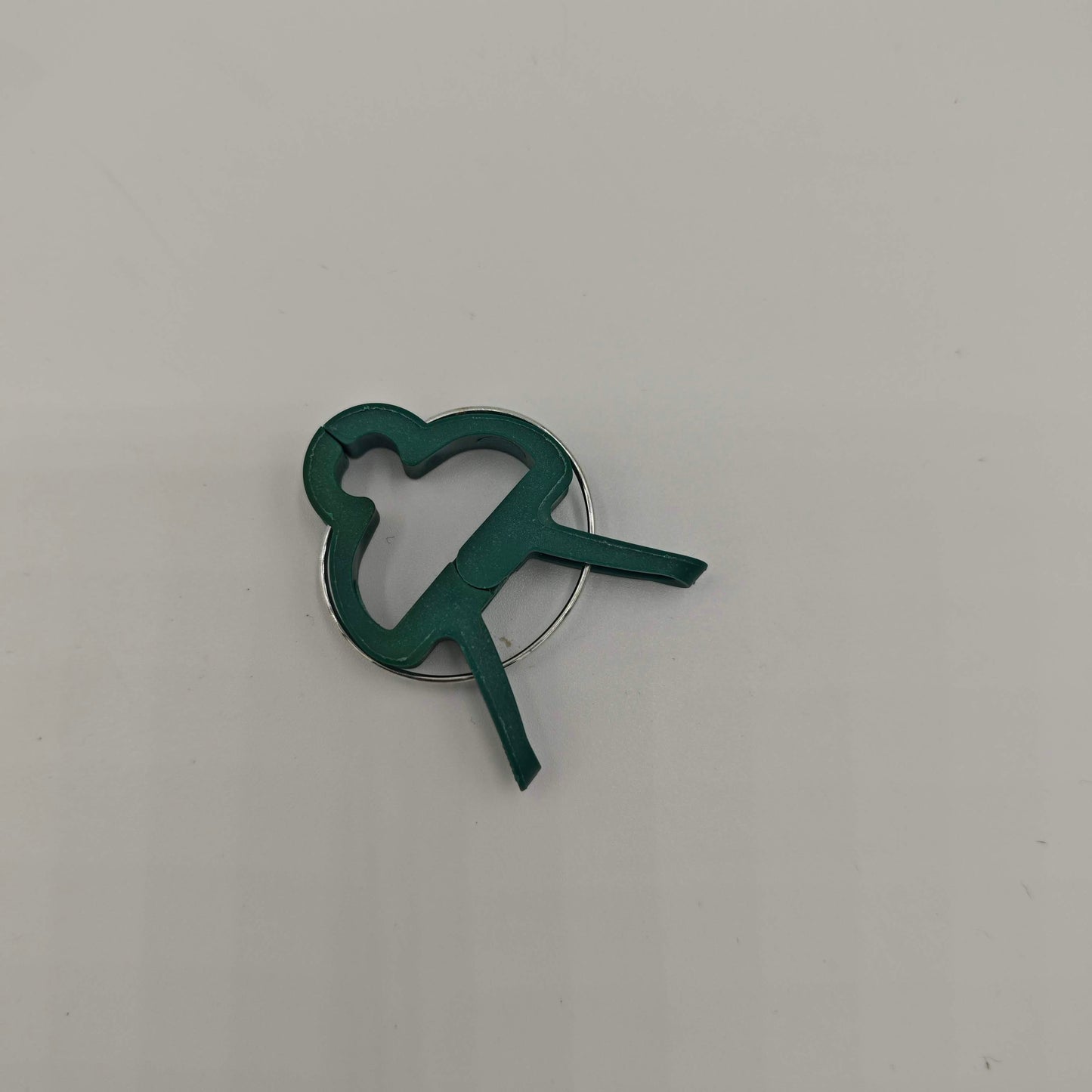 Gros plan sur un seul clip de support pour plantes en plastique vert, avec sa forme de papillon.