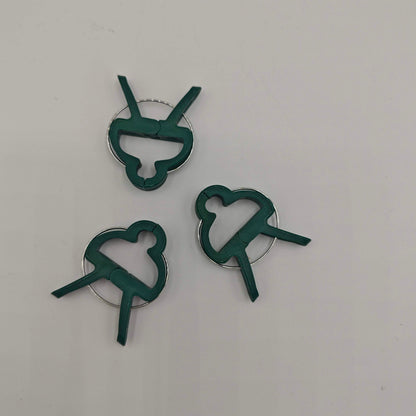 Un lot de trois clips de support pour plantes en plastique vert avec un ressort métallique, conçus pour fixer les tiges aux tuteurs.