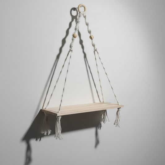 Étagère murale suspendue en macramé et bois clair, photographiée en studio avec un éclairage directionnel créant des ombres graphiques pour accentuer son design.