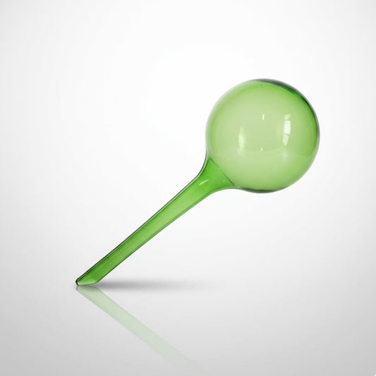 Globe d'arrosage automatique en verre vert translucide sur un fond dégradé gris et blanc avec un reflet élégant.