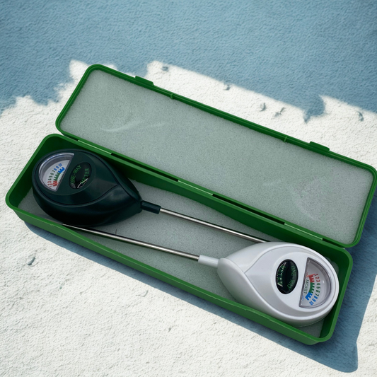 Deux sondes d'humidité pour plantes (une noire et une blanche) rangées dans leur boîte de transport verte, posées sur une surface texturée. Idéal pour mesurer l'humidité du terreau.