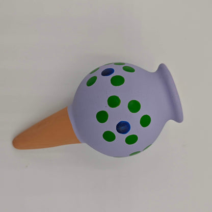 Un cône d'arrosage goutte à goutte pour plantes d'intérieur, en céramique peinte en mauve avec des points verts et bleus.
