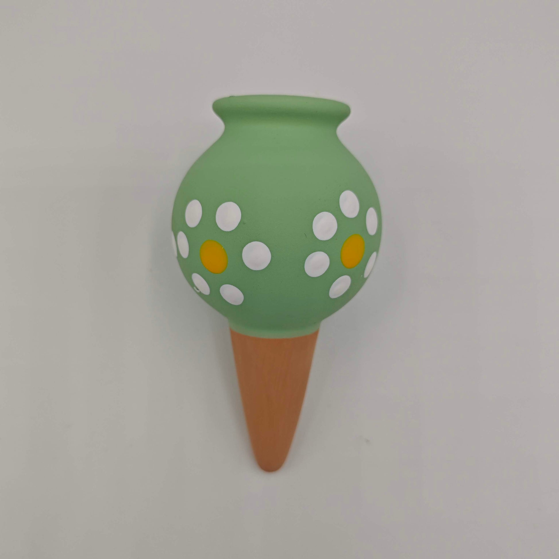 Un cône d'arrosage en céramique verte à pois blancs et jaunes, à insérer dans la terre d'un pot pour arroser les plantes par capillarité.