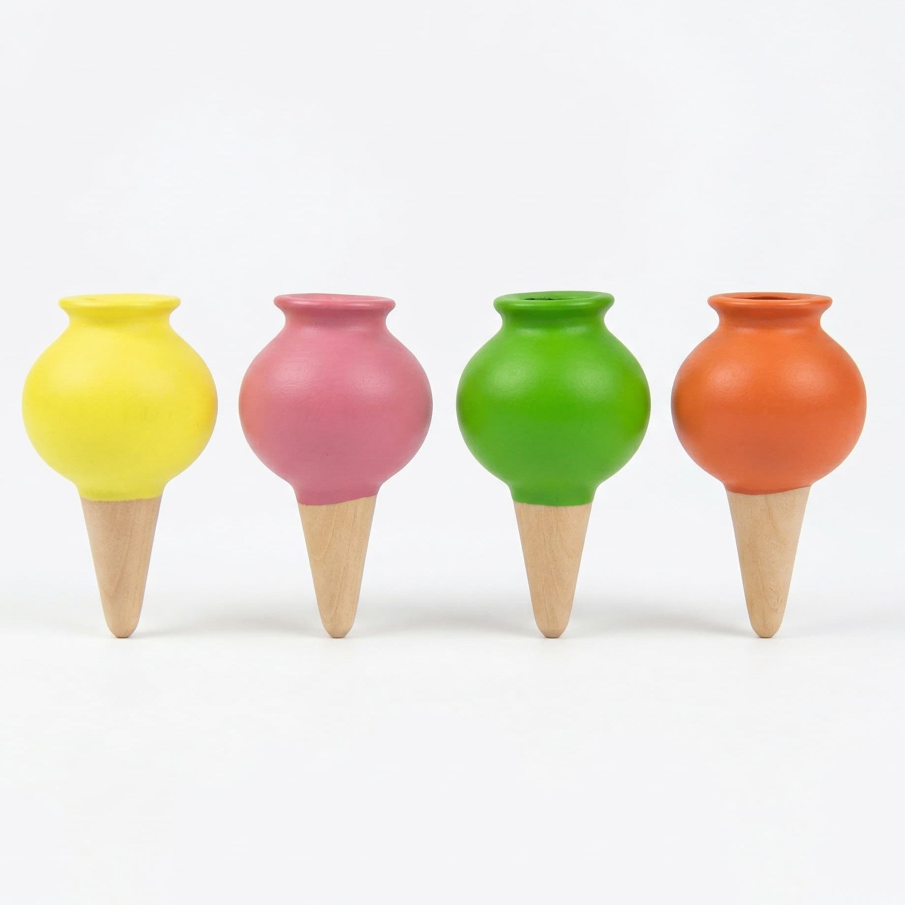Alignement de quatre petites ollas en céramique aux couleurs vives (jaune, rose, vert, orange) avec pointes en terre cuite naturelle sur un fond blanc uni.