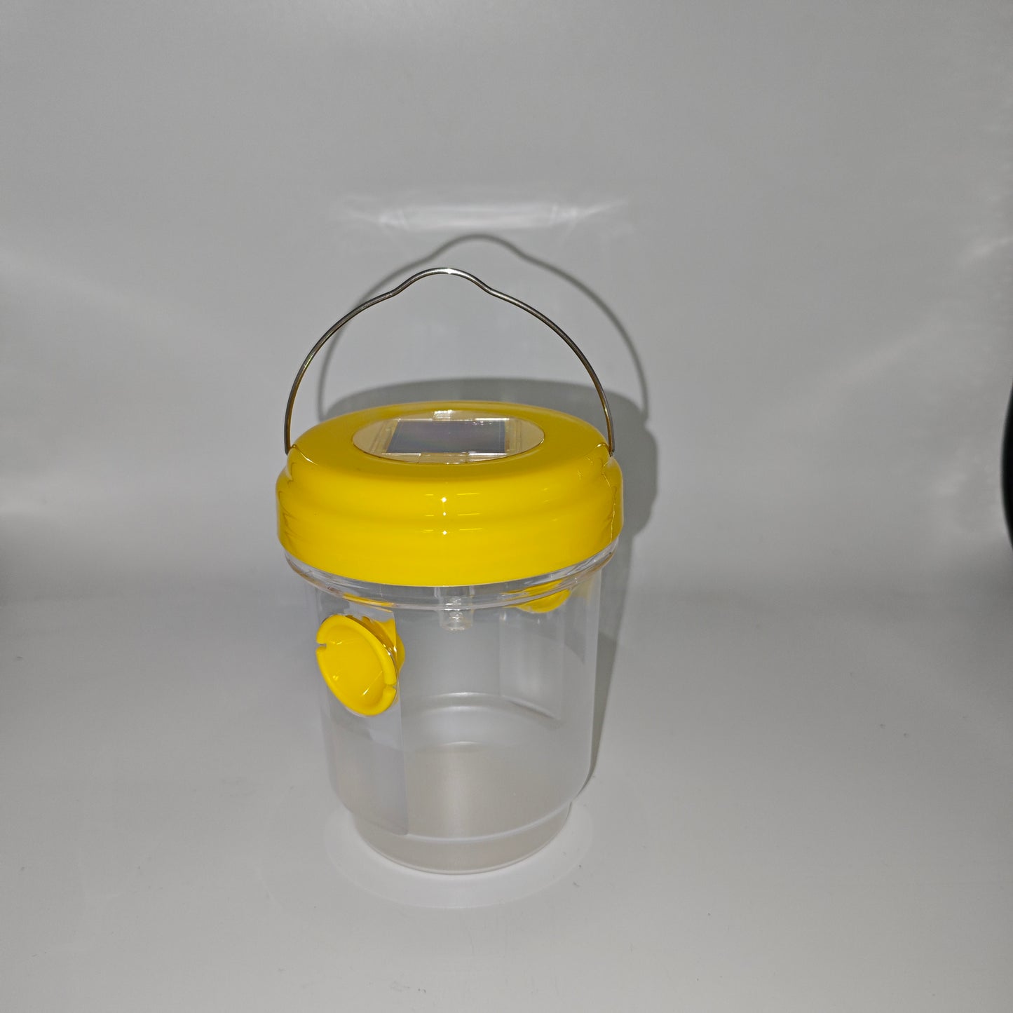 Un piège à guêpes ou à insectes cylindrique avec un couvercle jaune et un panneau solaire intégré, conçu pour une utilisation en extérieur.