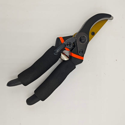 Un sécateur de jardinage ergonomique à poignées noires et lame dorée, posé sur un fond blanc.